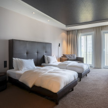Modernes Hotelzimmer mit getrennten Betten und großen Fenstern. 