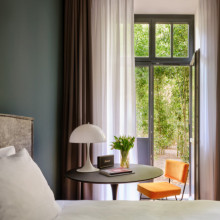 Hotelzimmer im sly Berlin mit Terrasse & Ein kleiner Tisch mit einer Marshals Musikbox vor der Terrassentür.